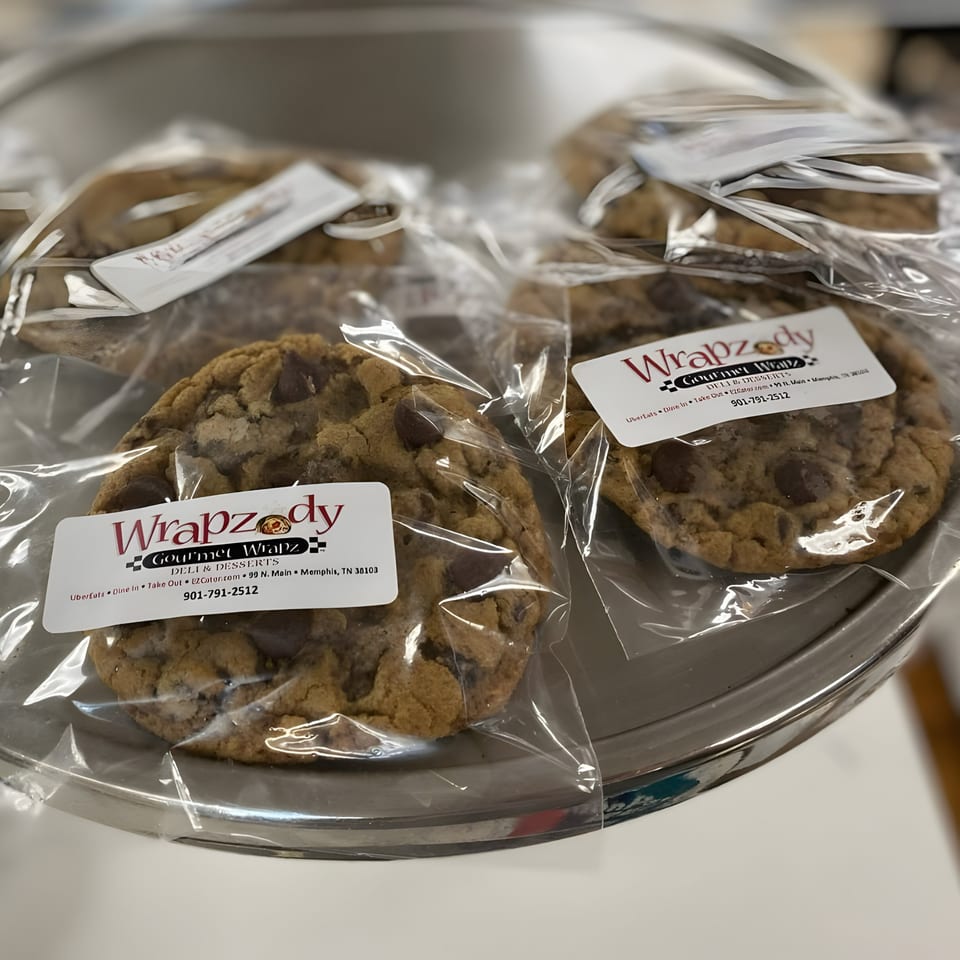 Several individually wrapped chocolate chip cookies from Wrapzody Gourmet Wrapz Deli on a silver tray.
